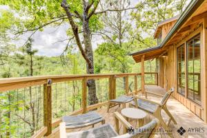 a cabin with a deck with chairs and a table at The Cottonwood in Treehouse Grove at Norton Creek in Gatlinburg