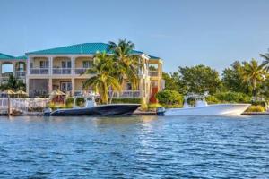 a house on the water with a boat in front of it at Grand Marina Suite by Brightwild-Waterfront Condo in Key West