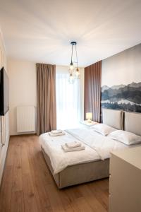 a bedroom with a large bed and a chandelier at Cozy Luxury Apartments Maurer Residence #Targu Mures in Târgu-Mureş
