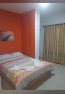 een slaapkamer met een bed met oranje muren en een raam bij Kapowlito Real Estate Casa Cocobiacoweg in Paramaribo