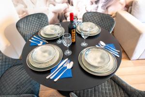 a black table with plates and glasses and a bottle of wine at Cozy Luxury Apartments Maurer Residence #Targu Mures in Târgu-Mureş