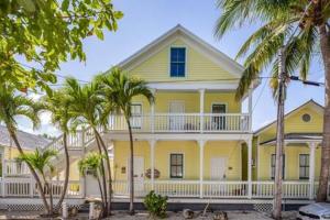 a yellow house with palm trees in front of it at Coral Cove #1 by Brightwild in Key West