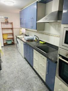 een keuken met blauwe kasten, een wastafel en een vaatwasser bij Apartamento La cala 2 in Cala del Moral