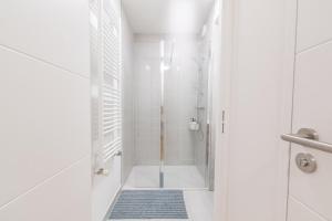 uma casa de banho branca com um chuveiro e um tapete azul em BoChic - Modernité et Sérénité aux Portes de Paris em Romainville