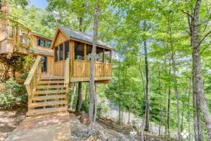 uma casa na árvore na floresta com um deque em The Mulberry in Treehouse Grove at Norton Creek em Gatlinburg