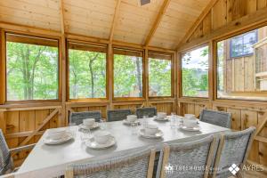 uma sala de jantar com mesa, cadeiras e janelas em The Mulberry in Treehouse Grove at Norton Creek em Gatlinburg