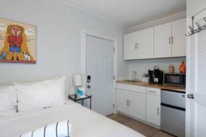 a white bedroom with a white bed and a kitchen at Carey's Corner #10 by Brightwild in Key West