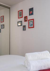 een slaapkamer met een wit bed met foto's aan de muur bij Chill and Work entre Paris et Disney in Neuilly-Plaisance