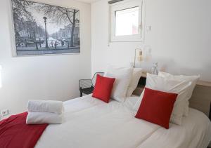 um quarto com uma cama branca e almofadas vermelhas em Chill and Work entre Paris et Disney em Neuilly-Plaisance