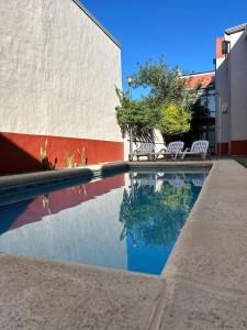 a swimming pool with two white chairs next to a building at Departamento en Colastine Norte in Colastiné