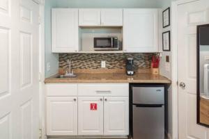 a kitchen with white cabinets and a sink at NEW VanGogh Studio by Brightwild- Pool & Balconies in Key West