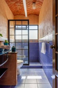 La salle de bains est pourvue de toilettes et d'une douche avec du carrelage bleu. dans l'établissement Hermosa Casa 20p/6Hab/Pool/Jacuzzi Tequisquiapan, à La Laja