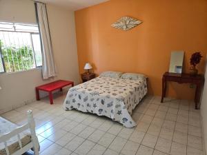 a bedroom with a bed and a table and a window at Casa para temporada in Vera Cruz de Itaparica