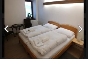 Bett mit weißen Kissen auf einem Zimmer in der Unterkunft Penzion U Koruny in Ústí nad Labem