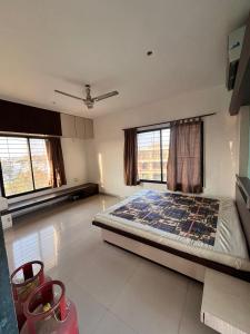 a bedroom with a bed in a room with windows at 2BHK Fully Furnished Penthouse With Living Hall And Kitchen Krishi Nagar Nashik in Nashik