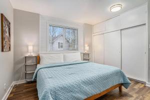 Un dormitorio con una cama con una manta azul y una ventana. en Lee Getaway, en South Haven