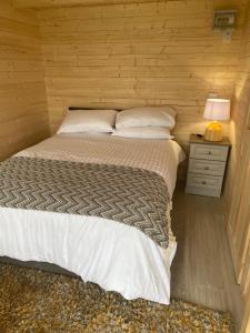 a bedroom with a bed and a night stand with a lamp at Country Cabin in Mullagh