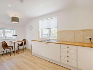 阿伯蒂費的住宿－3 Bed in Aberdovey 91520，厨房配有白色橱柜、桌子和窗户。