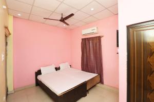 a bedroom with a bed and a pink wall at OYO SHRI RAM Homestay in Kāthgodām
