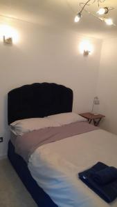 a bedroom with a bed with a black headboard at Cwtch By The Sea in Porthcawl