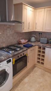 a kitchen with a stove and a washing machine at Cwtch By The Sea in Porthcawl