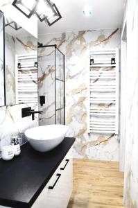 a bathroom with a white sink and a marble wall at Apartament Aleksandra in Tolkmicko