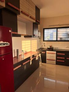 a kitchen with black cabinets and a red refrigerator at 2BHK Fully Furnished Penthouse With Living Hall And Kitchen Krishi Nagar Nashik in Nashik