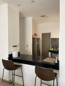 uma cozinha com um balcão preto e duas cadeiras em Casa con Alberca en colonia Vista Hermosa em Reynosa