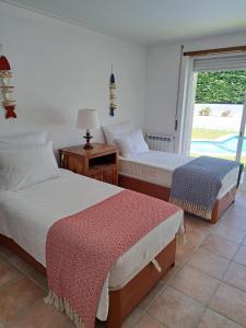 two beds in a room with a window at Sea wave sounds, Meco, by the beach in Sesimbra