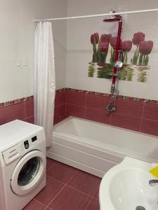 a bathroom with a washing machine next to a bath tub at GUEST House in Qusar