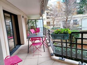 eine Terrasse mit rosa Stühlen und einem Tisch auf dem Balkon in der Unterkunft Magnifique Appartement à 500 mètres du Métro in Levallois-Perret