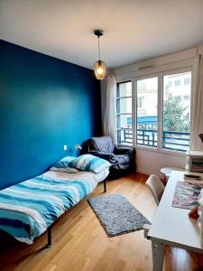 Zimmer mit einem Bett und einer blauen Wand in der Unterkunft Magnifique Appartement à 500 mètres du Métro in Levallois-Perret