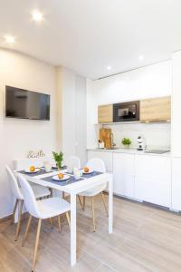 cocina blanca con mesa blanca y sillas en Precioso apartamento con Jardín a 500m de la Playa en Altafulla