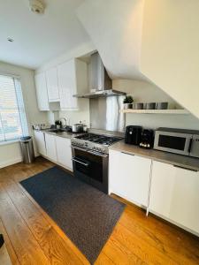 cocina con armarios blancos y fogones negros en Stunning Flat in Chiswick, en Londres