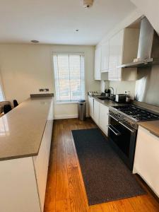 uma cozinha com armários brancos e um forno de fogão preto em Stunning Flat in Chiswick em Londres