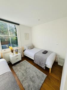 a white bedroom with two beds and a window at Stunning Flat in Chiswick in London