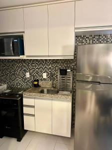 a kitchen with white cabinets and a stainless steel refrigerator at Muro Alto Clube Residence in Ipojuca