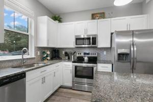 una cucina con armadietti bianchi ed elettrodomestici in acciaio inossidabile di NEW! Canopy Cove, Luxury Downtown Apartment Near Main St a Safety Harbor
