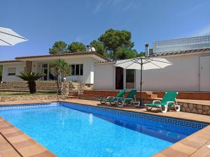 uma piscina com duas cadeiras e um guarda-sol em Casa L'Escala, 4 dormitorios, 8 personas - ES-89-127 em Torroella de Montgrí