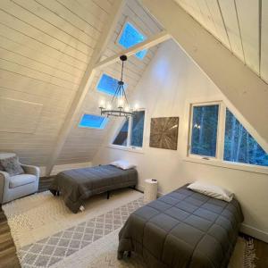 レイク・アローヘッドにあるLake Arrowhead Lux Black Cabinのベッド2台とシャンデリアが備わる屋根裏部屋です。 +16枚の写真