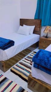 a bedroom with two beds with blue sheets and a lamp at Sama Stars Hotel in Abu Simbel