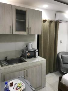 a small kitchen with a sink and a microwave at RESIDENCE FABY 1 in Dakar