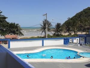 a swimming pool with people in it next to the beach at Apartamento 101 com vista da piscina e mar in Piúma