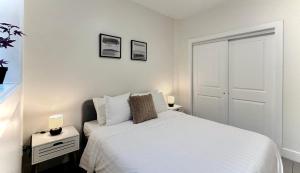 a white bedroom with a bed and two night stands at Blissful Stay in Surrey in Surrey +20 photos