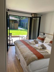 a large bed in a bedroom with a large window at la Villa des Cap - à 400m Océan et Bassin in Cap-Ferret