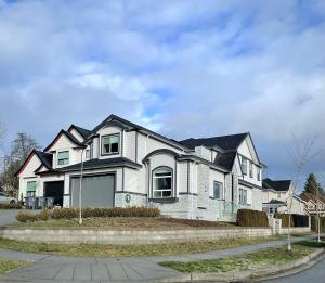 a white house with a black roof on a street at Blissful Stay in Surrey in Surrey