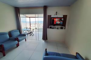 Frente ao mar casa 42 Praia do Estaleiro في أوباتوبا: غرفة معيشة مع كرسيين ازرق وتلفزيون