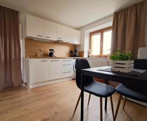 a kitchen with white cabinets and a table and chairs at Domek na vinohradech in Hlohovec