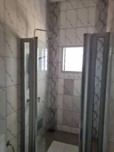 ein Bad mit einer Glastür und einem Fenster in der Unterkunft Résidence Schilo - appartement équipé avec piscine privée et rooftop in Abomey-Calavi