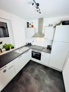a white kitchen with a sink and a stove at Apartment LEO in Berghausen